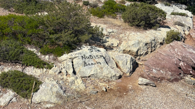 the words "naturist beach" painted by hand on a rock
